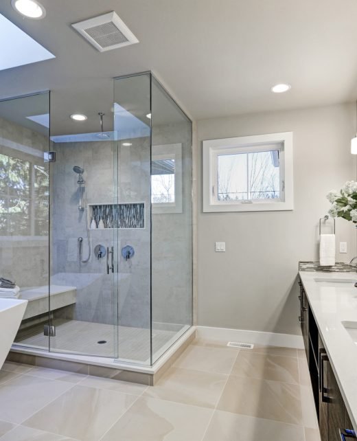 Spacious bathroom in gray tones with heated floors, freestanding tub, walk-in shower, double sink vanity and skylights. Northwest, USA